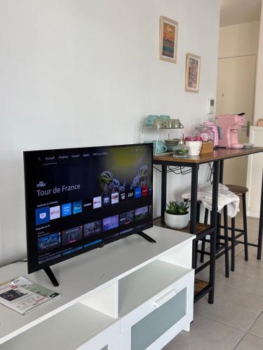 a flat screen tv sitting on top of a tv stand at Côté Parc - appt entier neuf et cosy, parking & au pied du métro à Lyon in Vénissieux