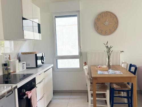 a kitchen with a table and a clock on the wall at Côté Parc - appt entier neuf et cosy, parking & au pied du métro à Lyon in Vénissieux
