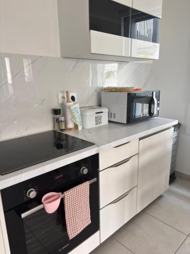 a kitchen with a black and white stove top oven at Côté Parc - appt entier neuf et cosy, parking & au pied du métro à Lyon in Vénissieux