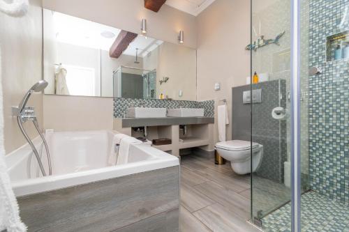 a bathroom with a tub and a toilet and a sink at Whale Rock Luxury Lodge in Hermanus