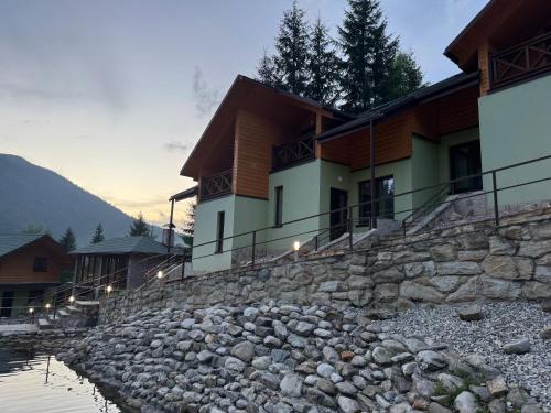 a house with a stone wall next to a river at Karpasole in Tatariv
