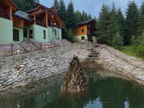 a stone retaining wall next to a river with houses at Karpasole in Tatariv