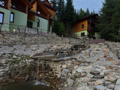 a stone retaining wall next to a house with a waterfall at Karpasole in Tatariv