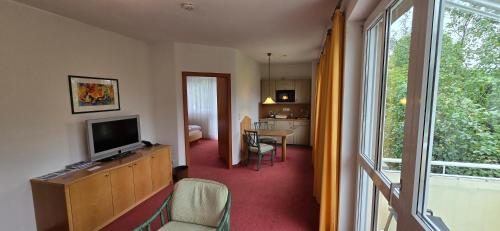 a living room with a television and a table with chairs at Hotel Alpina in Bad Reichenhall
