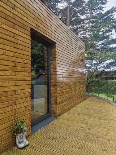 a wooden house with a large glass door on a deck at Ty Branwen in Cowbridge