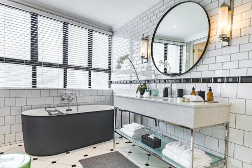a bathroom with a tub and a sink and a mirror at Cape Cadogan Boutique Hotel in Cape Town