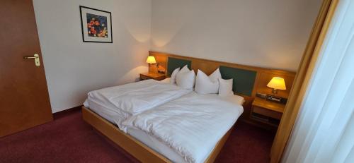 a hotel room with a bed with white sheets and pillows at Hotel Alpina in Bad Reichenhall