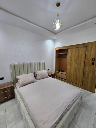 a bedroom with a large bed and a wooden cabinet at Appartement vue piscine in Saidia 