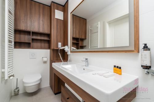 a bathroom with a sink and a toilet and a mirror at Your Holidays Bel Mare 407D in Międzyzdroje