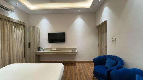 a room with a bed and two blue chairs at The Aana Hotel Sohna -Gurgaon Road in Gurgaon