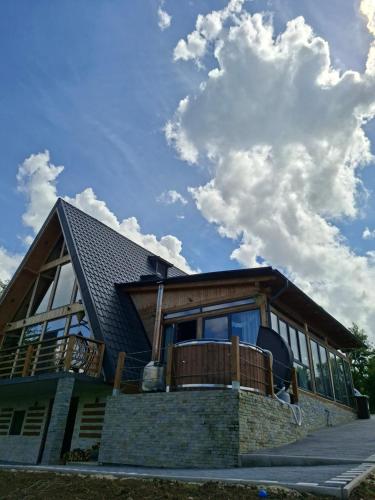 a house with a roof and a sky with clouds at Cabana 3 Stejari Maramureș in Călineşti