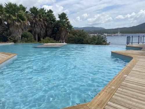 - une piscine à côté d'un corps d'eau dans l'établissement APPT T3 terrasse dans résidence bord de mer avec piscine, à Pianottoli-Caldarello