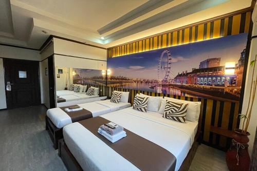 a room with three beds with a painting on the wall at Angeles Palace Hotel in Angeles