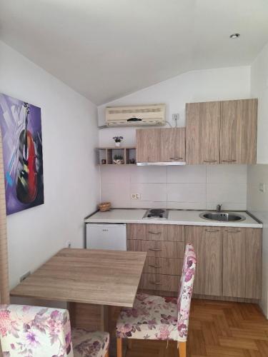 a kitchen with a wooden table with two chairs at Apartments & Rooms Vuksanovic Ivana in Budva