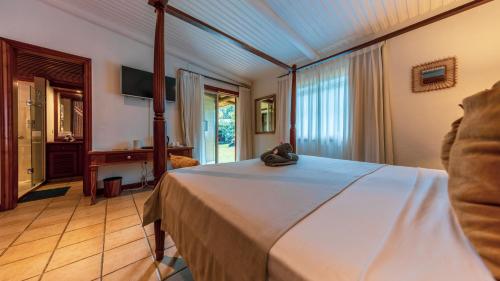 a bedroom with a large bed and a desk at Shanti Ghar Guest House in Tamarin