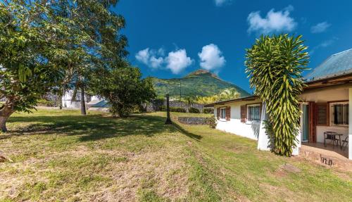 a house with a mountain in the background at Shanti Ghar Guest House in Tamarin