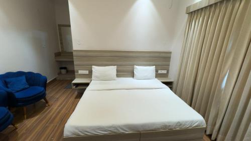 a room with two beds and a blue chair at The Aana Hotel Sohna -Gurgaon Road in Gurgaon