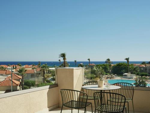 a balcony with tables and chairs and a view of the ocean at Lindos Princess Beach Hotel in Lardos
