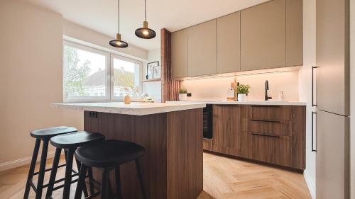 a kitchen with wooden cabinets and bar stools at Riia street apartment with parking in Tartu