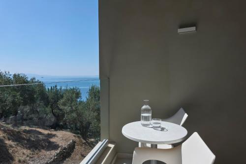 a white table and chairs in a room with a window at Atlantica Nissaki Beach - Adults Only in Gimari