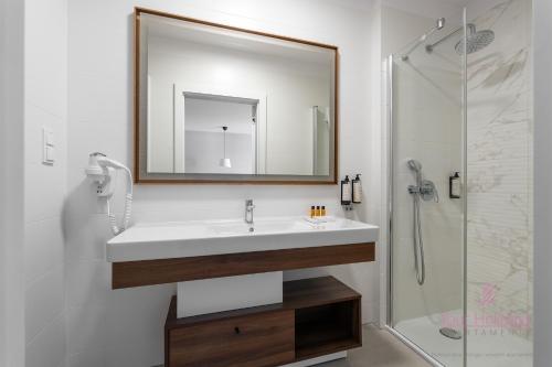 Un baño con lavabo y ducha con espejo. en Your Holidays Bel Mare 402D, en Międzyzdroje
