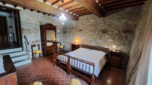 Un dormitorio con una cama y una pared de piedra. en Agriturismo Poggiolo, en Castiglion Fiorentino