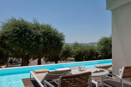 a patio with a table and chairs next to a swimming pool at Atlantica Nissaki Beach - Adults Only in Gimari