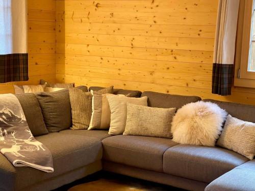 a gray couch with pillows and a white furry pillow at Charming Chalet With Splendid Views Near Gstaad in Lauenen