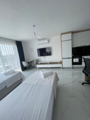 a white room with two beds and a tv at Four seasons sitesi in Aglantzia