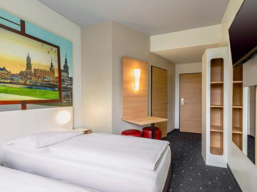 a hotel room with two beds and a desk at B&B Hotel Dresden-Messe in Dresden