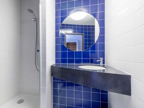 a blue tiled bathroom with a sink and a mirror at B&B Hotel Dresden-Messe in Dresden