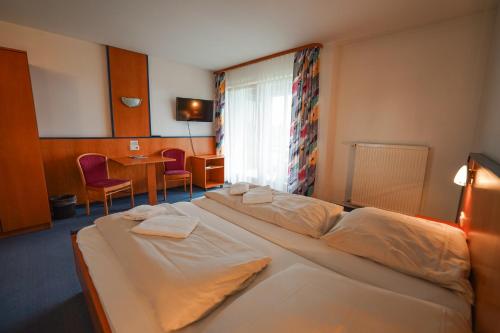 a hotel room with a large bed and a table at Hotel Sonnenhof - Tante ALMA`s Sommerfrische in Sonnen