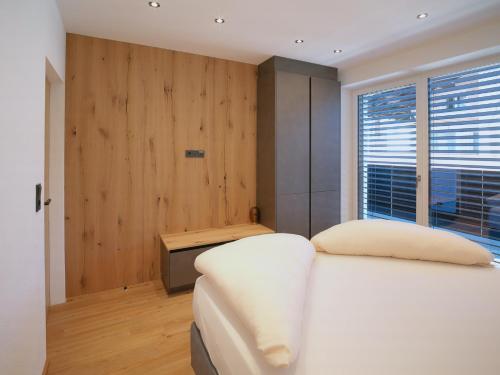 a bedroom with a white bed and a wooden wall at BLACKSTYLE - Stylish Apartment with Balcony & Parking in Tyrol, presented by AlpenLuxus in Brixlegg
