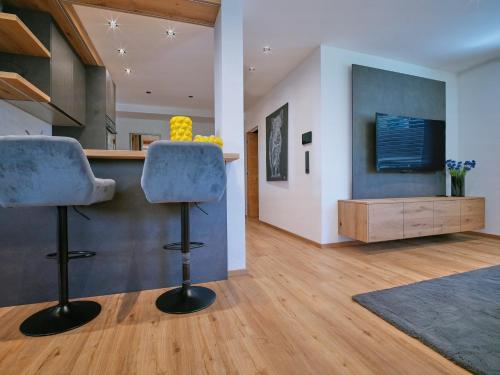 a kitchen with two bar stools and a tv at BLACKSTYLE - Stylish Apartment with Balcony & Parking in Tyrol, presented by AlpenLuxus in Brixlegg