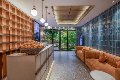 a lobby with a couch and a bowl of fruit at Orange Hotel Beijing Niujie Subway Station in Beijing
