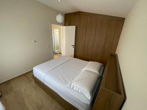 a bedroom with a white bed and a wooden cabinet at Garden beach house in Hamallë