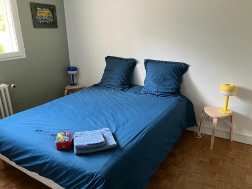 a bed with blue sheets and two towels on it at Chambre indépendante 10min circuit 24h tramway in Le Mans
