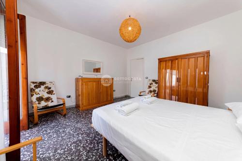 una camera da letto con un grande letto bianco e una sedia di La Casina Di Mare a Porto Cesareo