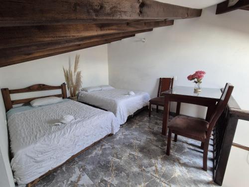 two beds in a room with a desk and a table at Apto Beija Flor - Gran Capacidad in Villa de Leyva