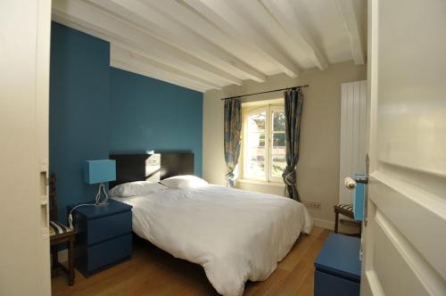 a blue bedroom with a white bed and a window at Gite du Château du Magnet in Mers-sur-Indre