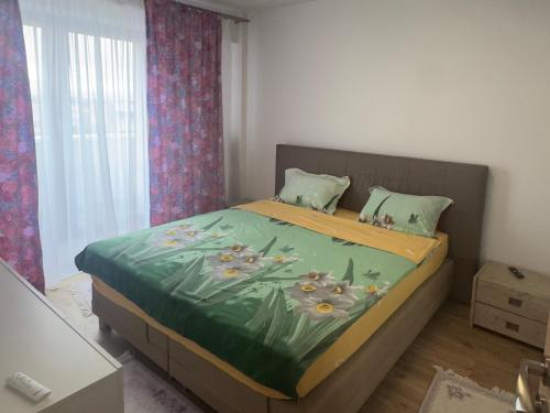a bedroom with a bed with a green blanket at Apartament RYO in Şelimbăr