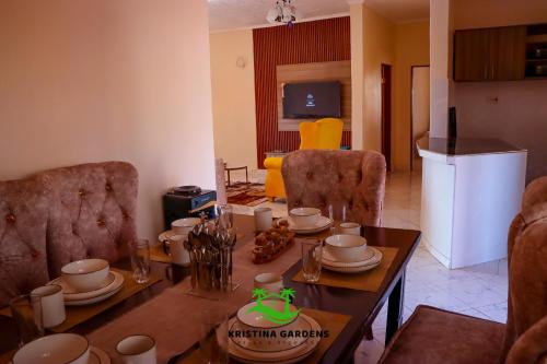 a living room with a table and a kitchen with a refrigerator at Kristina Gardens in Voi