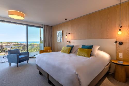 une chambre d'hôtel avec un grand lit et une chaise dans l'établissement Les Jardins Du Cèdre, à Port-Vendres