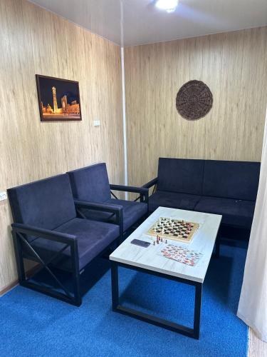 a living room with two blue couches and a chess board on a table at Chorvoq View in Chorwoq