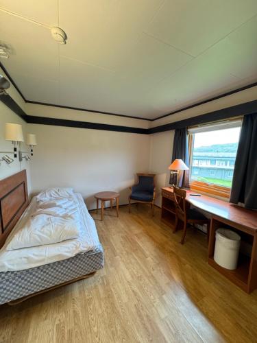 a bedroom with a bed and a desk and a window at Camp Skytterhuset in Hammerfest
