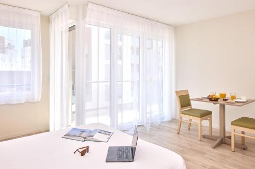 a room with a bed with a laptop and a chair at Zenitude Hôtel-Résidences Le Havre Les Docks in Le Havre