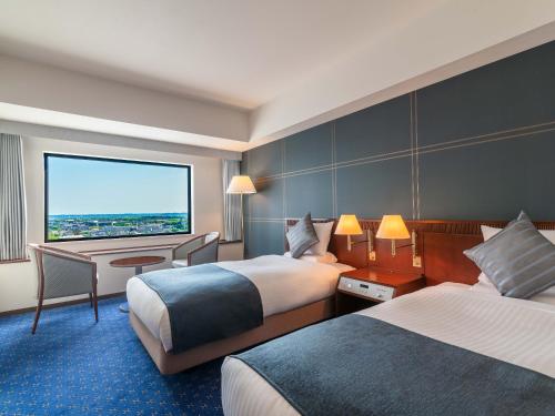 a hotel room with two beds and a large window at ART HOTEL Kashima Central in Kamisu