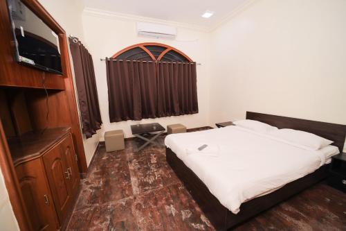 a bedroom with a bed and a flat screen tv at M3 Homestay in Madurai