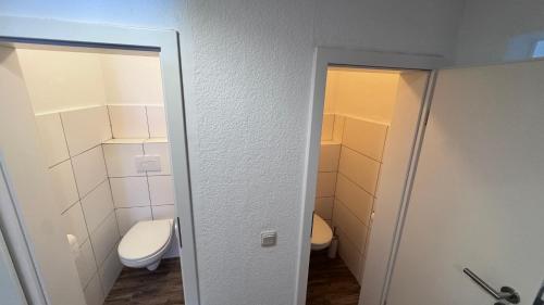 a bathroom with a toilet and a bathroom door open at 24-7 Living - Unna Central City Apartments in Unna