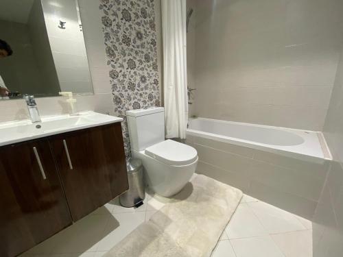a bathroom with a toilet and a tub and a sink at Dubai Silicon Oasis Holiday Homes in Dubai